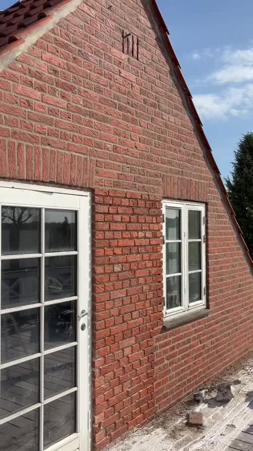 Rød murstensfacade med hvide vinduer under facadebehandling